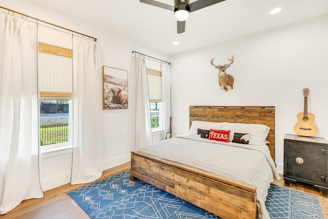 bedroom with multiple windows, hardwood / wood-style floors, and ceiling fan