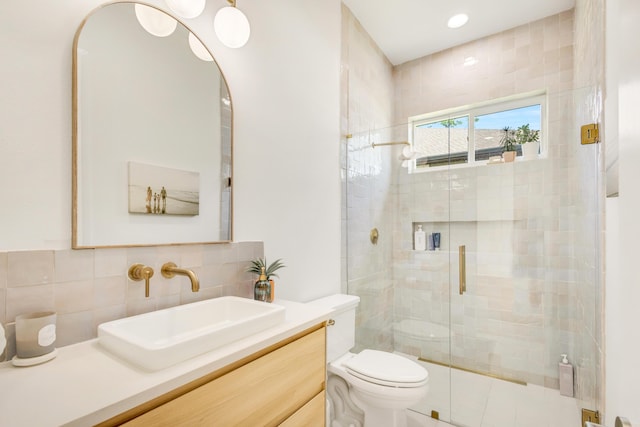 bathroom featuring vanity, decorative backsplash, a shower with door, and toilet