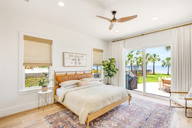 bedroom with a water view, ceiling fan, light wood-type flooring, and access to outside