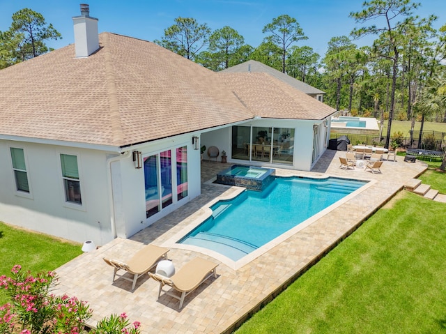 back of property with a yard, a pool with hot tub, and a patio