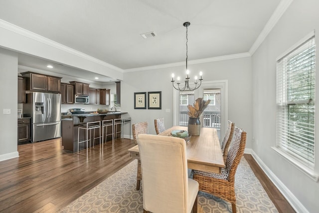 dining area featuring dark wood-type flooring, crown molding, and an inviting chandelier