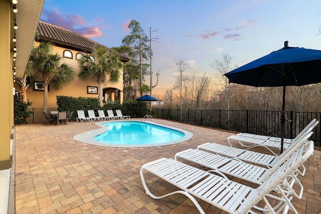 pool at dusk featuring a patio