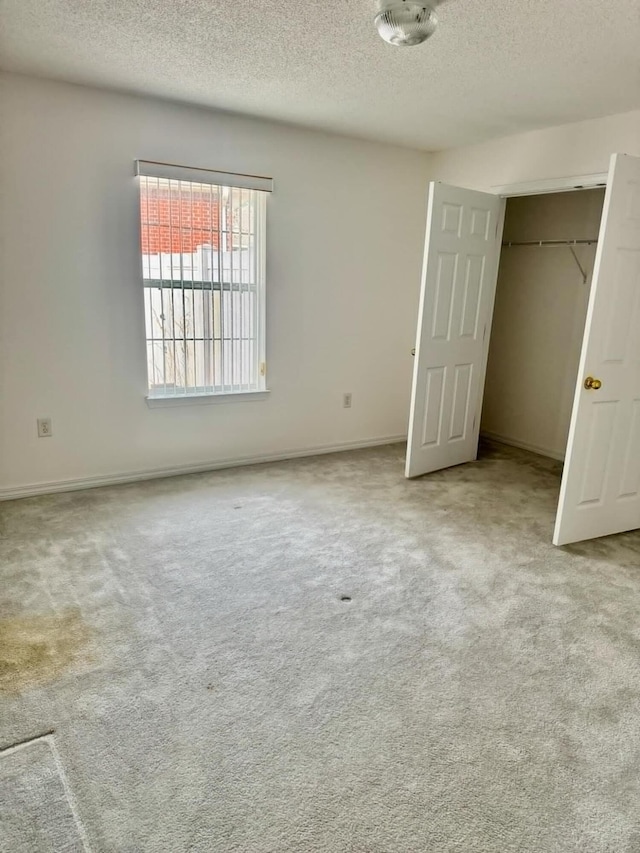 unfurnished bedroom featuring a closet, a textured ceiling, and carpet flooring