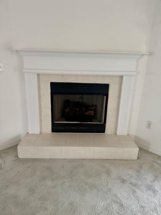 interior details featuring a tile fireplace and carpet flooring