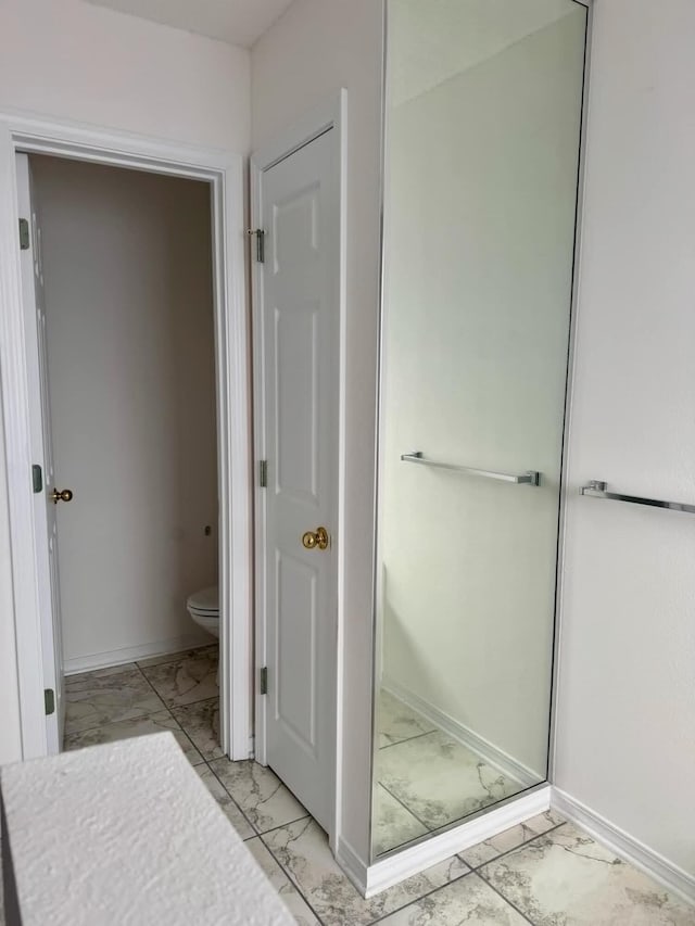 bathroom featuring marble finish floor, toilet, and baseboards