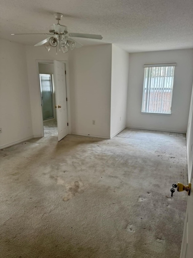 empty room featuring a textured ceiling, a ceiling fan, and light colored carpet