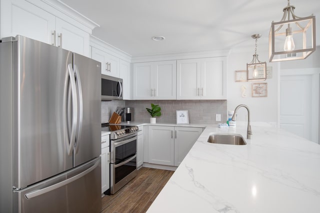 kitchen with pendant lighting, sink, appliances with stainless steel finishes, tasteful backsplash, and white cabinets