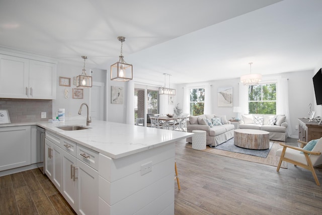 kitchen with sink, decorative light fixtures, kitchen peninsula, and white cabinets