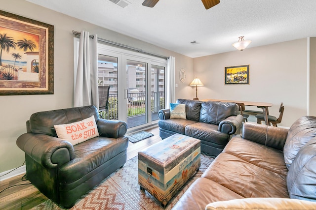 living room featuring ceiling fan and a textured ceiling