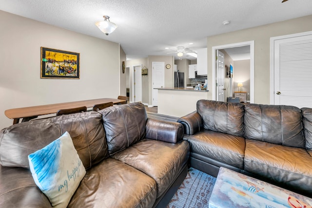 living room with ceiling fan and a textured ceiling