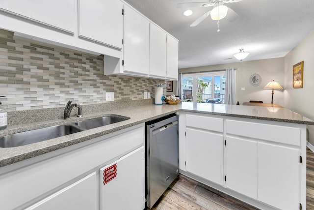 kitchen featuring white cabinetry, sink, hardwood / wood-style flooring, stainless steel dishwasher, and kitchen peninsula