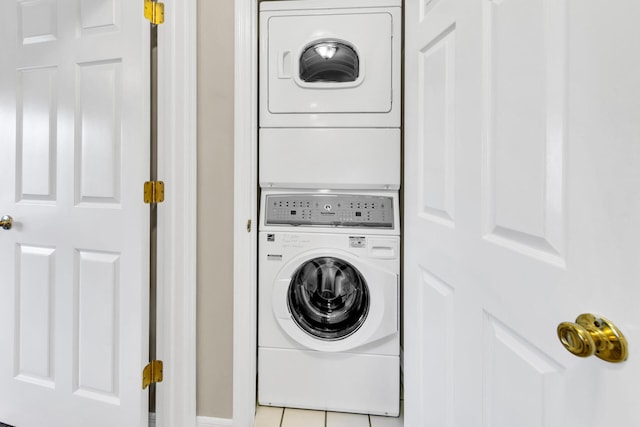 washroom featuring stacked washing maching and dryer and light tile patterned flooring