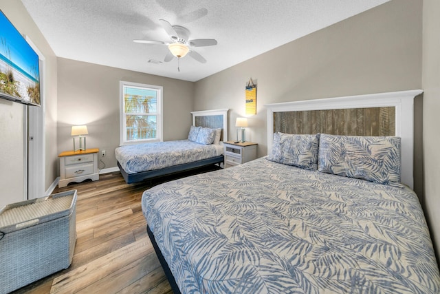 bedroom featuring ceiling fan, light hardwood / wood-style flooring, and a textured ceiling