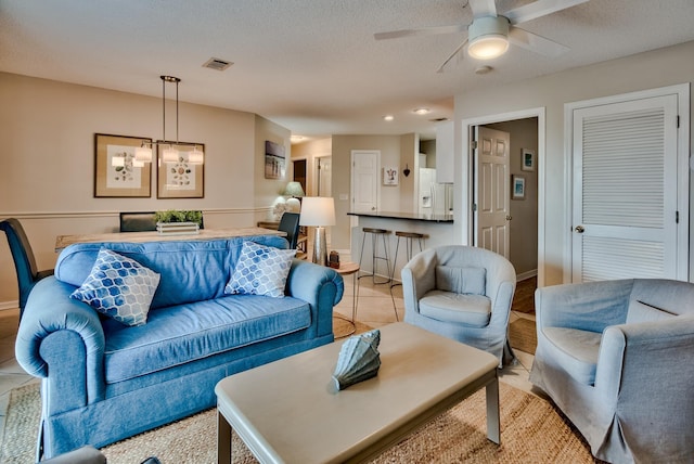 tiled living room with a textured ceiling and ceiling fan