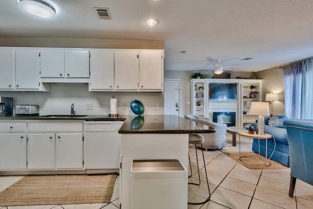 kitchen with a textured ceiling, white cabinets, white dishwasher, and light tile patterned floors