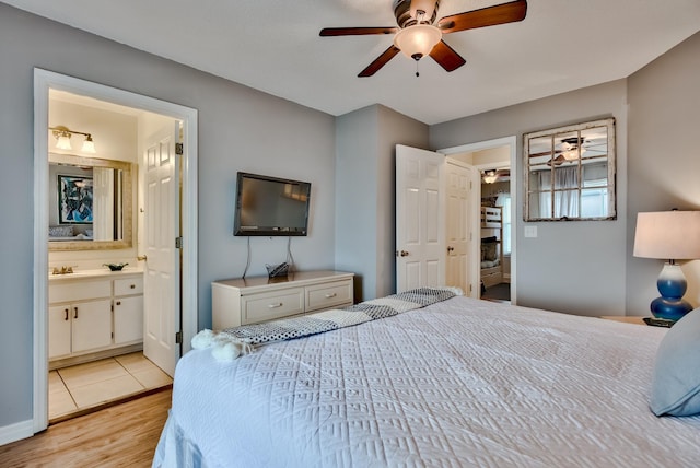 bedroom with ceiling fan, light wood-type flooring, and ensuite bath