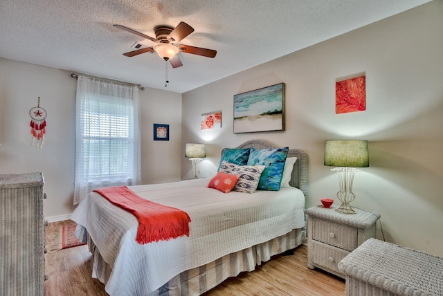 bedroom with a textured ceiling, ceiling fan, and light wood-type flooring