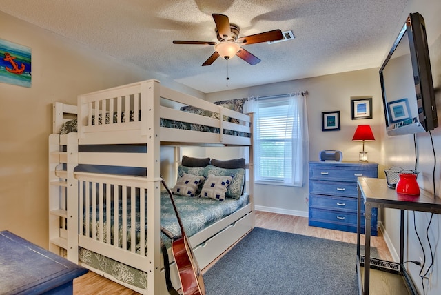 bedroom with a textured ceiling, ceiling fan, and light hardwood / wood-style floors