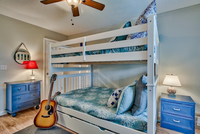 bedroom with ceiling fan, light hardwood / wood-style flooring, and a textured ceiling