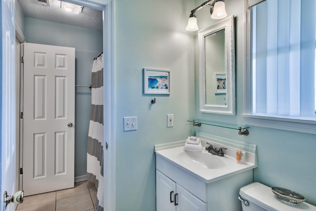 bathroom with tile patterned flooring, vanity, a textured ceiling, and toilet