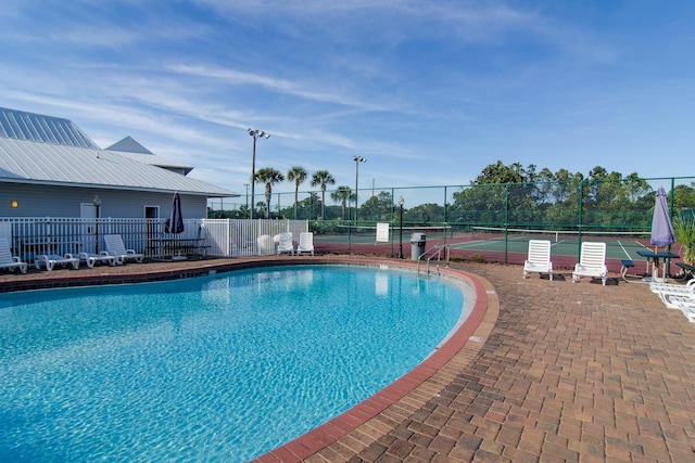 view of swimming pool with tennis court