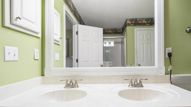 bathroom featuring walk in shower, vanity, and a textured ceiling