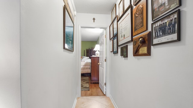 hall with a textured ceiling and light tile patterned floors