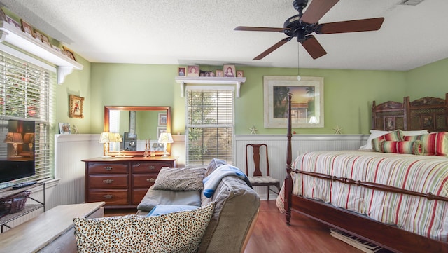 bedroom featuring ceiling fan, hardwood / wood-style floors, and a textured ceiling