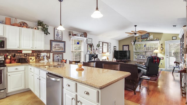 kitchen with appliances with stainless steel finishes, decorative light fixtures, white cabinetry, sink, and kitchen peninsula