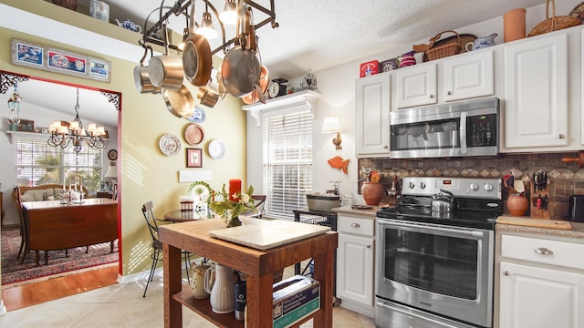 kitchen featuring backsplash, a notable chandelier, stainless steel appliances, and white cabinets