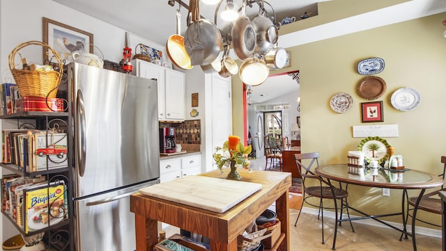 kitchen with vaulted ceiling, white cabinets, stainless steel refrigerator, and decorative light fixtures