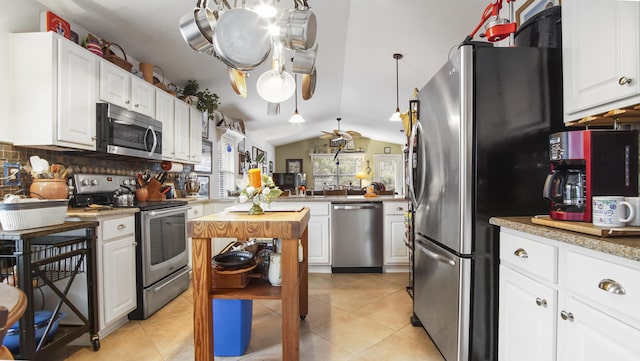 kitchen with vaulted ceiling, appliances with stainless steel finishes, light tile patterned floors, and white cabinets