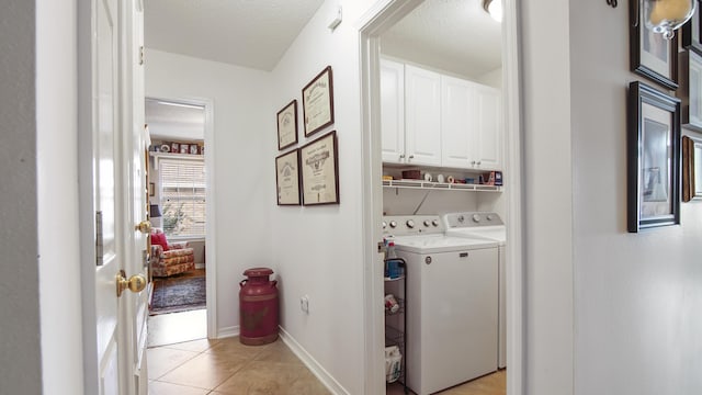 laundry room featuring light tile patterned floors, washer and clothes dryer, cabinets, and a textured ceiling