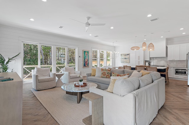 living room featuring light parquet flooring and ceiling fan with notable chandelier