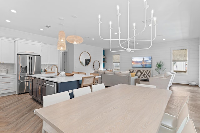 dining room featuring light parquet flooring, a healthy amount of sunlight, sink, and a notable chandelier