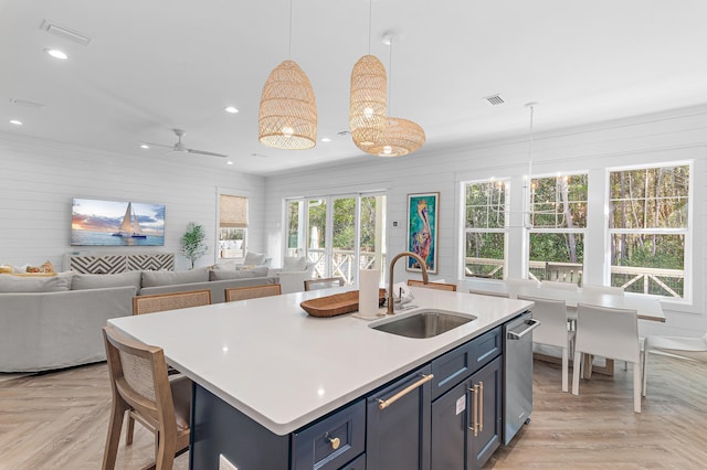 kitchen with sink, decorative light fixtures, blue cabinetry, and light parquet floors