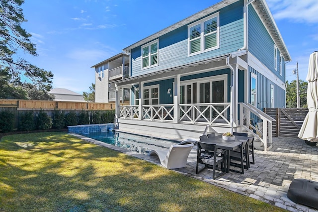 rear view of property featuring a balcony, a yard, a fenced in pool, and a patio