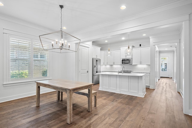 dining area featuring sink, dark wood-type flooring, ornamental molding, and a chandelier