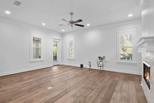 unfurnished living room featuring a tiled fireplace, ornamental molding, and light wood-type flooring