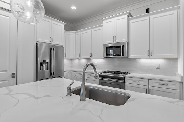 kitchen with pendant lighting, white cabinets, decorative backsplash, light stone counters, and stainless steel appliances