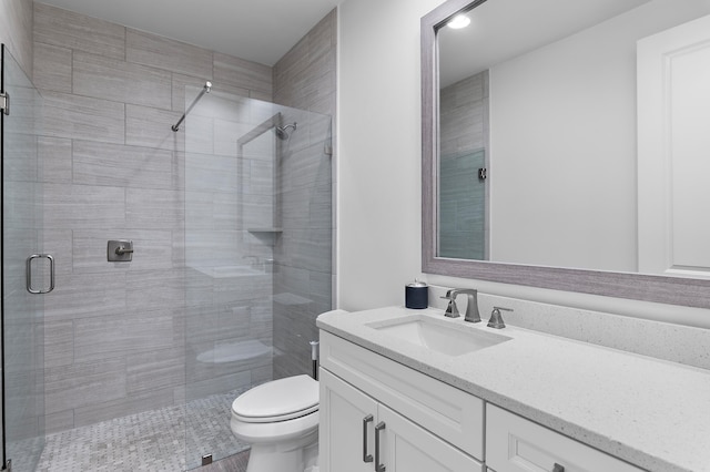 bathroom featuring vanity, a shower with door, and toilet