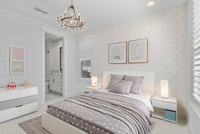 bedroom featuring ensuite bath and a chandelier