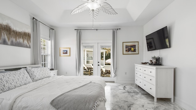 bedroom featuring multiple windows, a tray ceiling, access to outside, and french doors