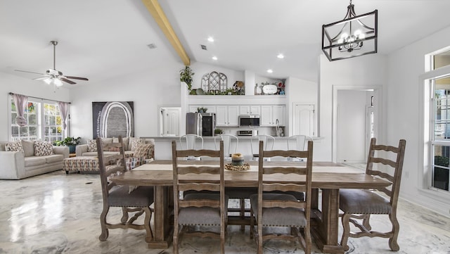 dining space featuring ceiling fan with notable chandelier, beam ceiling, and high vaulted ceiling