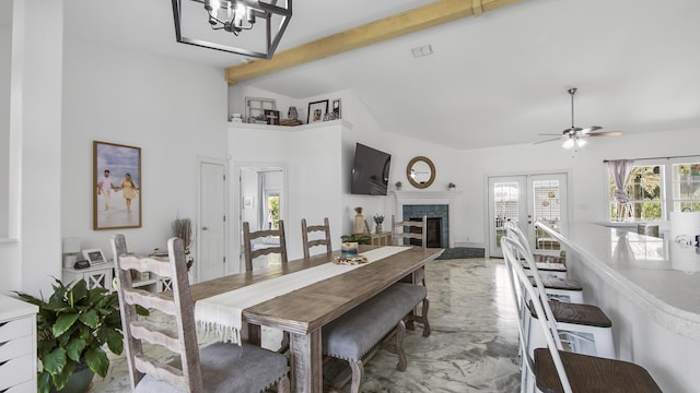 dining area featuring high vaulted ceiling, beamed ceiling, a tiled fireplace, ceiling fan, and french doors