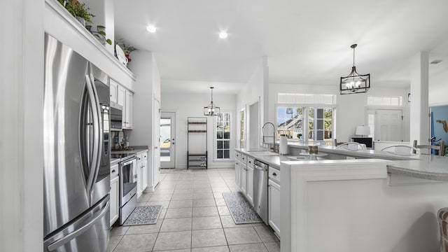 kitchen with appliances with stainless steel finishes, sink, hanging light fixtures, and white cabinets