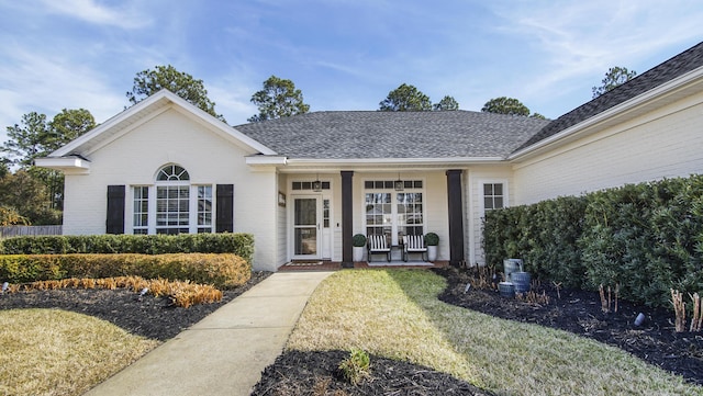 view of exterior entry featuring covered porch and a lawn