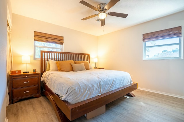 bedroom with ceiling fan, light hardwood / wood-style floors, and multiple windows