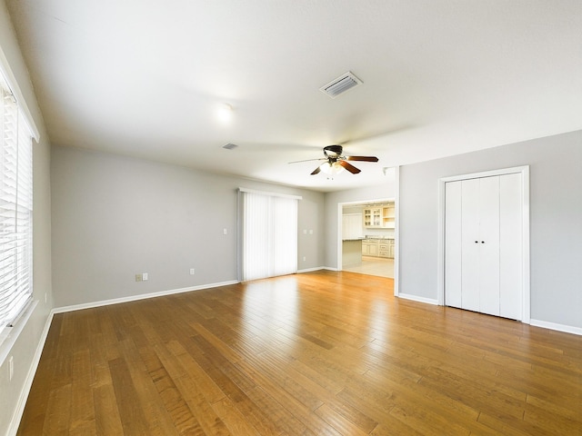 unfurnished living room with baseboards, wood finished floors, visible vents, and a ceiling fan