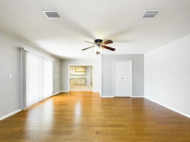 unfurnished room featuring visible vents, ceiling fan, light wood-style flooring, and baseboards